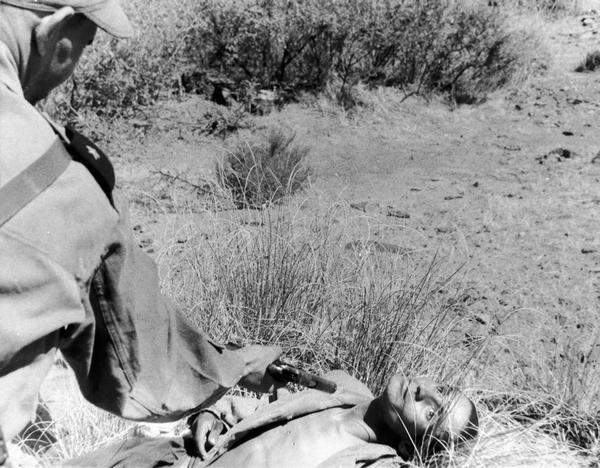 Executed man laying on ground as the final bullet is delivered. The execution was somehow bungled by the firing squad and this coup d'grace was required to be done by the battalion's guest, a headquarters colonel. Algeria.