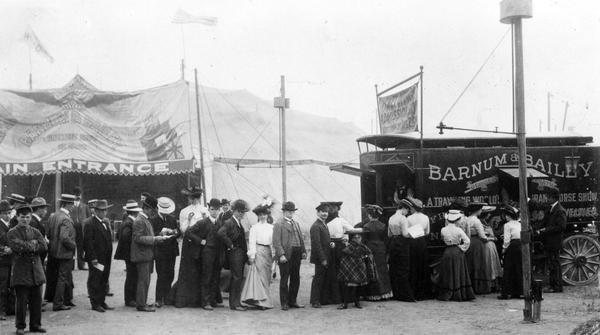 People stand in line to purchase tickets at a Barnum & Bailey Circus ticket wagon near the main tent.