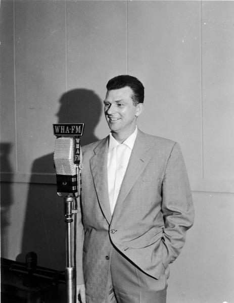 Ken Ohst stands at WHA-FM microphone with hands in pockets.