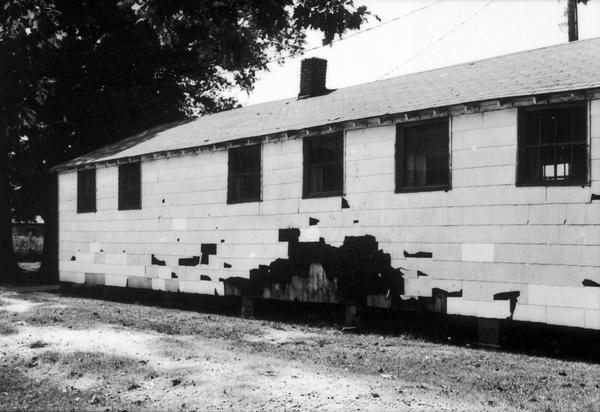 Back view of a black high school showing damage on a wall. SNCC Arkansas Project.