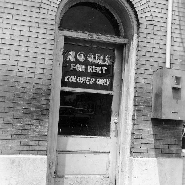 Exterior of building showing door with the sign "Rooms for rent. Colored only". SNCC Arkansas Project.