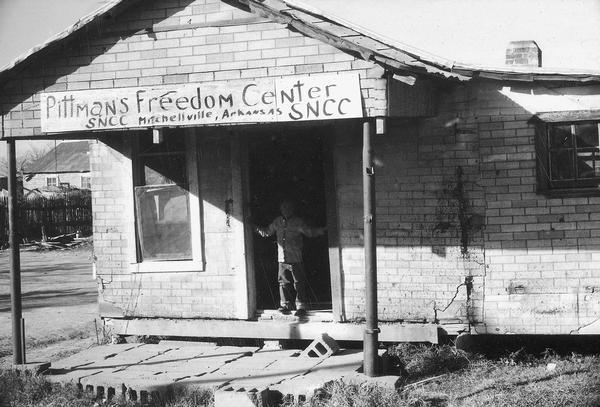Exterior view of the Freedom House, which was a Student Nonviolent Coordinating Committee (SNCC) sponsored Freedom Center. SNCC Arkansas Project. A child stands in the doorway.