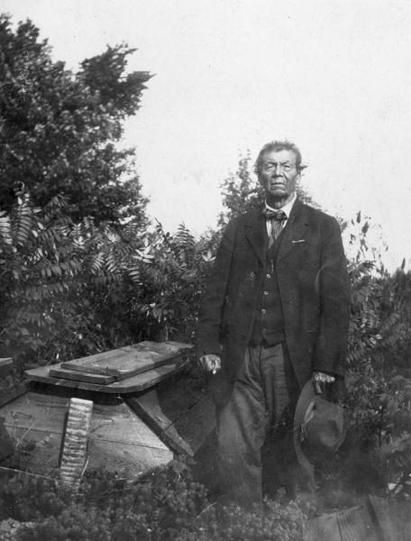 Menominee Judge Perrote beside the wooden grave of his wife. The Court of Indian Offenses was established in 1883 with Indian judges appointed by the U.S. Government. This image and the above caption is part of an exhibit about Native Americans prepared by Paul Vanderbilt, the Wisconsin Historical Society's first curator of photography.