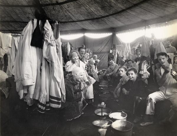 A group of 20+ circus clowns posing informally while preparing for the ring.