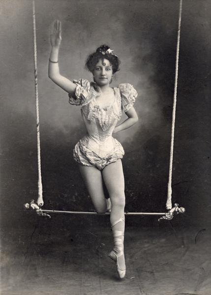Studio portrait of trapeze artist Emily Schadel, posing on a trapeze.