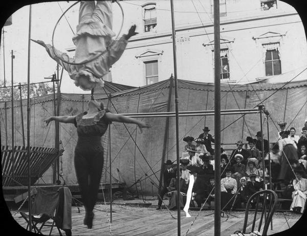 A street carnival on the Capitol Square in which two individuals perform together while suspended in the air.