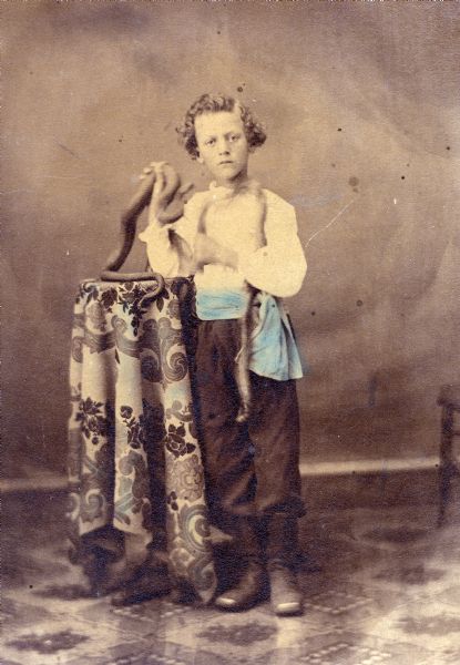 George W. Hall, Jr., noted Evansville, Wisconsin, circus performer, as a young boy, holding a snake and wearing copper-toed boots.