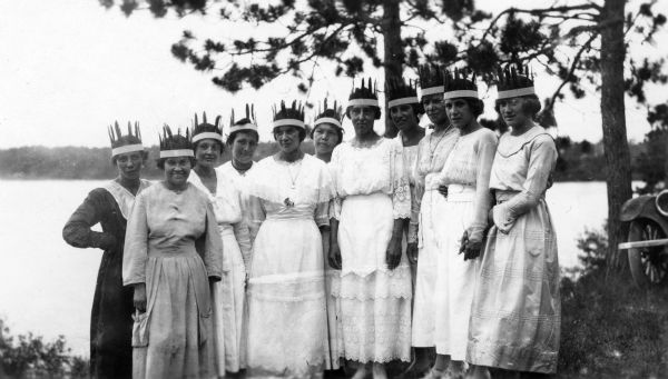 A group of Chippewa (Ojibwa) girls in white western clothing and paper feathered headdresses for a celebration commemorating the return of 80 Native American soldiers who served in World War I. This image is part of an exhibit about Native Americans prepared by Paul Vanderbilt, the first curator of photography at the Wisconsin Historical Society.