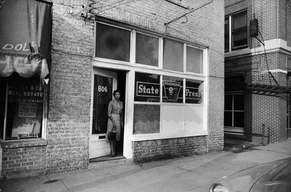 Daisy Bates standing in the doorway of the weekly <i>Arkansas State Press</i>, the newspaper founded by Mrs. Bates and her husband, L.C. Bates. As a result of the Bates' leadership in the integration struggle, pressure was placed on Press advertisers. Ultimately, sufficient advertisers withdrew their support, and the <i>Arkansas State Press</i> shut down in 1959.