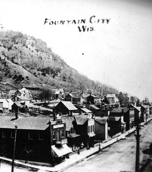 Elevated view of Fountain City, with bluffs in the background on the left. Caption reads: "Fountain City, Wis."