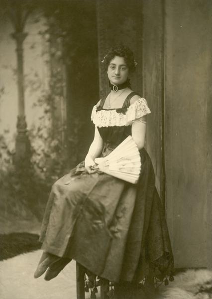 Seated portait of Amelia Feeley, supposedly the first circus bareback rider to perform in long dresses. Ms. Feeley hold a fan in her lap.