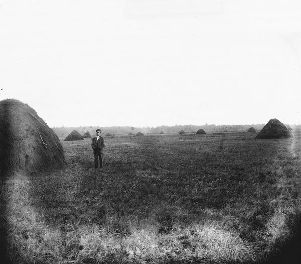 A lone man poses with haystacks in northern Wisconsin.