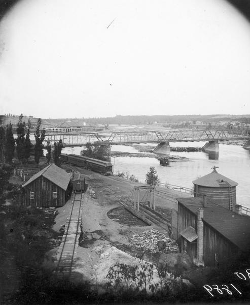 View of the Chippewa Lumber and Boom Company's Big Mill beyond the Wagon Bridge over the Chippewa River.
