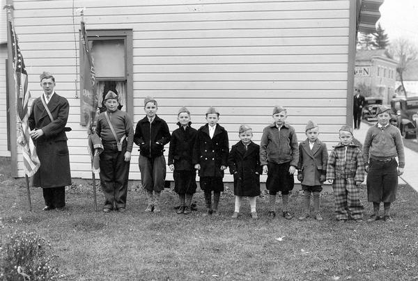 Sons of the American Legion in formation outside the Witt Studio. Two of them hold flags. Names are (left to right), Don Frank, Jerry Zander, Ralph Meyer, Harry Meyer, Mark Zander, Roland Frank, Val Frank, Paul Zander, Butch Bowar and Eddie Zander.