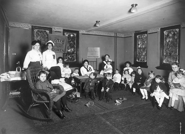 Thirteen children ranging from toddler-age to early elementary school-age are tended by several women in the playroom of a nursery run by the Kenosha County Equal Suffrage League.