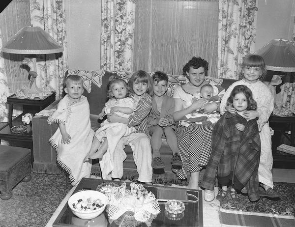 A mother posing with her seven children in the living room of their home.