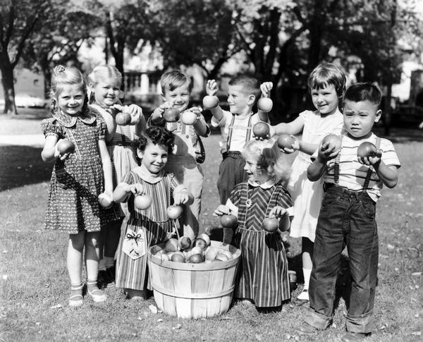 School children pose holding apples from a bushel basket in an effort to promote the Apple Institute.