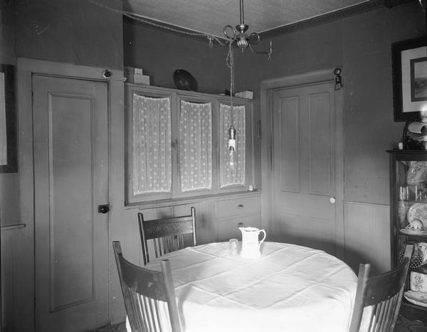Dining room in a small house showing a white pitcher on a table.