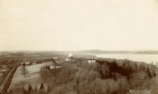 Elevated view of Observatory Hill on the University of Wisconsin Madison campus of the United States National, Wisconsin State Farm Experiment Station, Professor Watson' Solar Observatory, Washburn Observatory and the Director's house.  In the distance across the bay is Picnic Point on Lake Mendota.