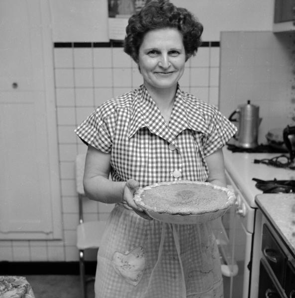 Mrs. Edna Kern, a farm wife, standing in her kitchen holding a pie. Her husband is Ernest G. Kern.