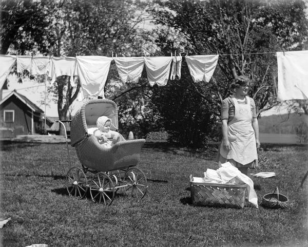 Baby Shirley Krueger watching from her carriage as her mother Elna Krueger is taking laundry off the clothesline.