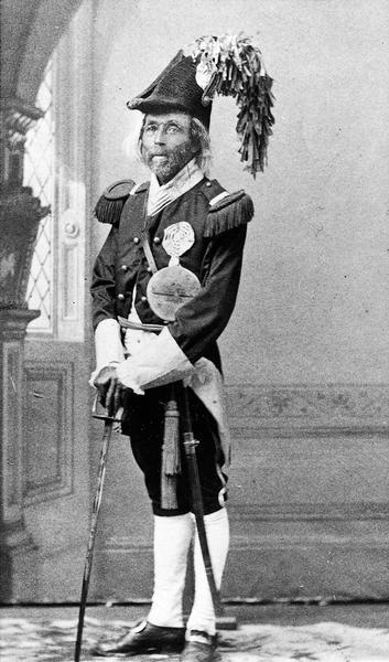 Studio portrait of "Professor" William H. Noland in costume as leader of the Mock Parade, or "Horribles". He was a barber, musician, chiropodist, and public functionary in Madison, WI.

Noland was a part of the 1866 mayoral election in Madison, as he was put forth as the Democratic party candidate against his will. He endorsed the Republican incumbent Elisha W. Keyes, but still received 306 votes, making him the first Black man to be nominated for mayor of Madison.

Noland was also the first Black man to be appointed to a state office as in 1857, Governor Coles Bashford appointed Noland as a notary public, though Secretary of State David W. Jones refused to file the bond due to Jones' bigotry toward African Americans. 