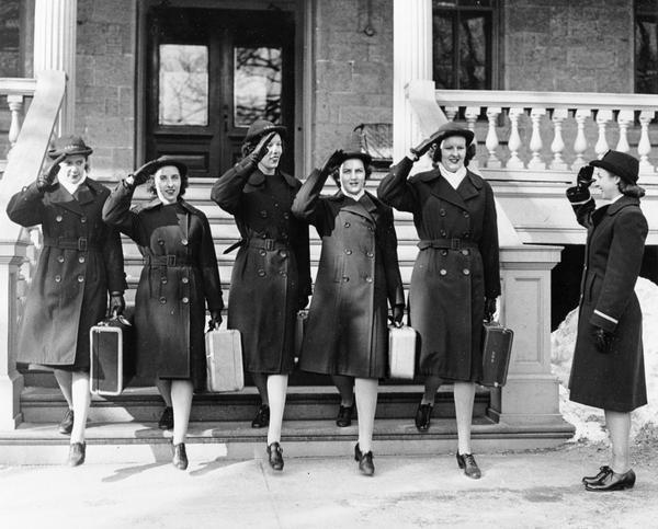 Five women dressed in WAVES (Women Accepted for Volunteer Emergency Service) uniforms saluting and carrying suitcases, probably at the University of Wisconsin, Madison.