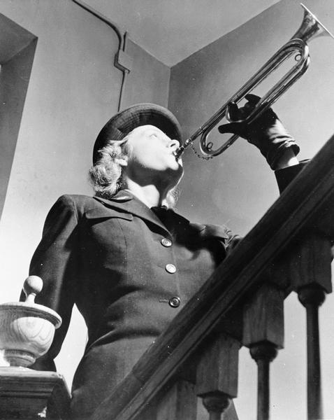 WAVES (Women Accepted for Volunteer Emergency Service) bugler, dressed in WAVES uniform, playing bugle on a staircase.