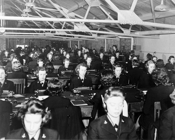 WAVES (Women Accepted for Volunteer Emergency Service) in a classroom sitting at typewriters listening to headphones studying code.