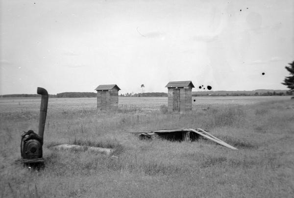 Two buildings, perhaps outhouses, and farm equipment in the vicinity of Crandon.