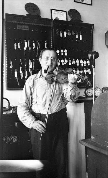 John Ciezczak (b.1885?), a Polish watchmaker, who sang songs in Polish, Ukrainian, Russian, and Kasshubian for song collector Helene Stratman-Thomas. He is smoking a pipe and playing a violin.