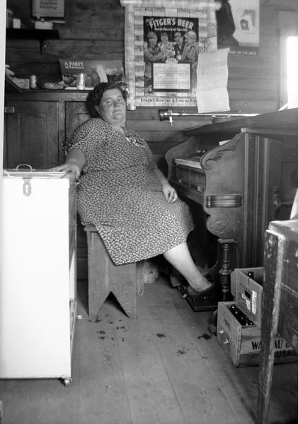 Bessie Gordon (b. 1901) at the cut-down reed organ under the tavern counter.