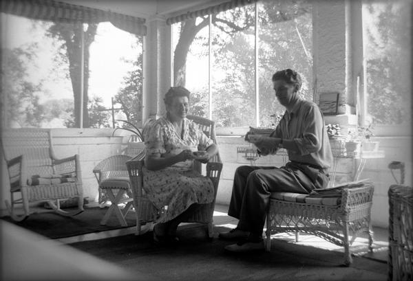 Donalda La Grandeur and an unidentified man sitting on a porch.