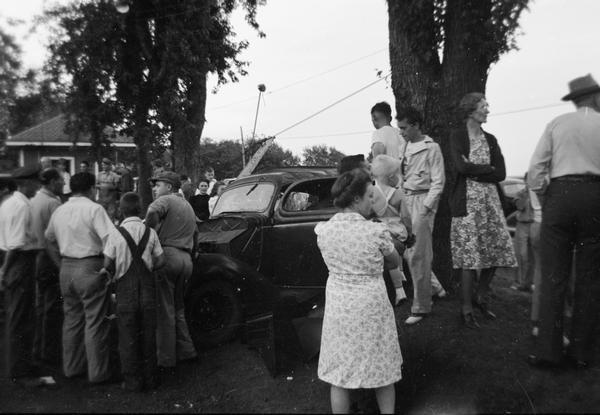 Group of people standing near a car.