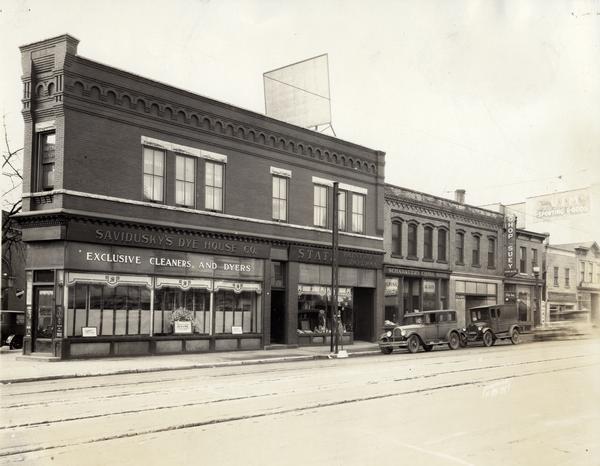 View of Savidusky's Dye House Company, State, Paint and Paper Company, Schadauer's China Shop, a drygoods store and Chop Suey Restaurant. The view also includes streetcar tracks and automobiles parked curbside.