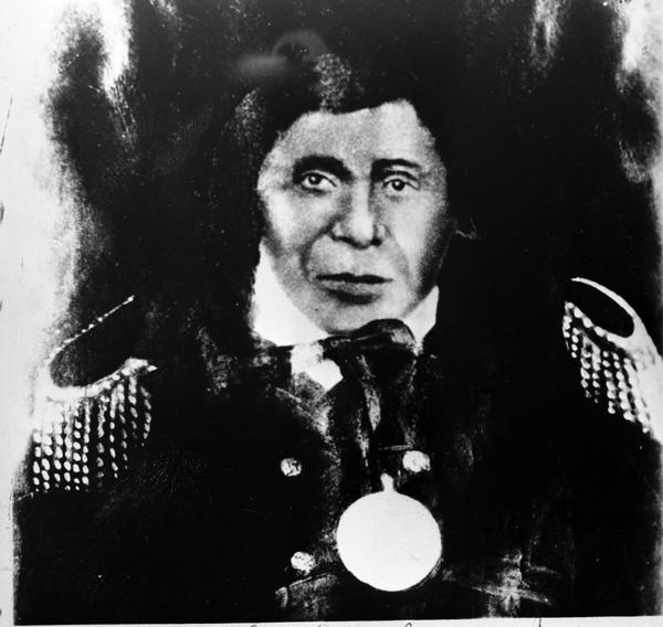 Portrait of Chief Buffalo, over-painted enlargement, possibly from a double-portrait (possibly an ambrotype). Grandson of Great Chief Buffalo.  Chief Buffalo was a principal Chief of the Lake Superior Band of Chippewa (Ojibwa). He was also known as Ke-che-waish-ke (Great Renewer), Peezhickee or Bishiki (Buffalo), and (in French) Le Beouf. He was born at La Pointe on Madeline Island in about 1759, and died 7 September 1855 at La Pointe.