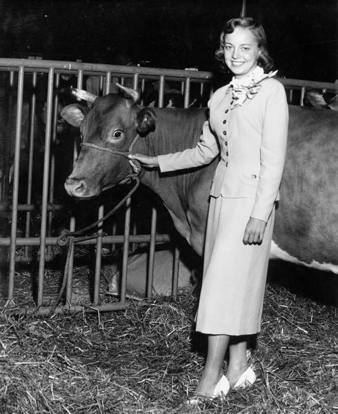 Beverly Steffen, the 1952 Alice in Dairyland, stands beside a cow at the Wisconsin State Fair.