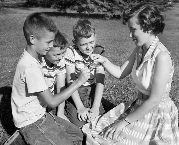 Mary Ellen Jenks, the 1953 Alice in Dairyland, inspecting a frog with three young boys.
