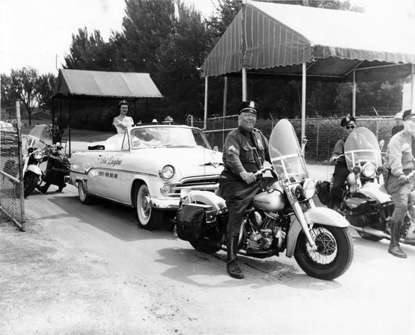 Mary Ellen McCabe, 1954 Alice in Dairyland, enters State Fair Park in her official convertible, escorted by police officers on Harley-Davidson motorcycles during the annual Wisconsin State Fair.