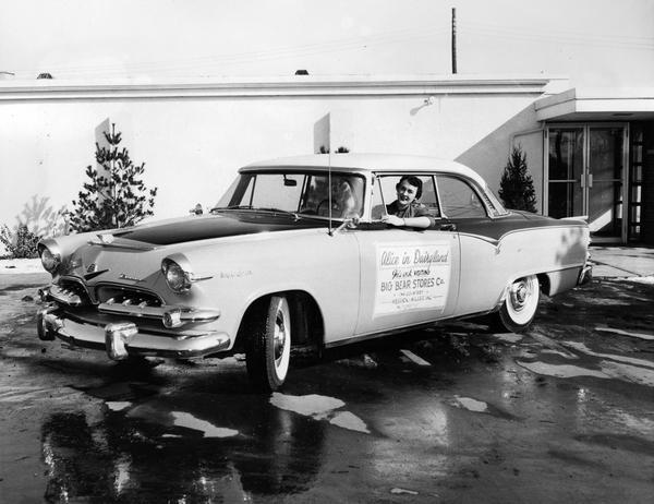 Mary Ellen McCabe, Alice in Dairyland, 1954-1955 takes delivery of her "car of the week," a Dodge Royal Lancer, that is to take her to her appearances at Big Bear stores.
