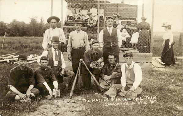 Group portrait of the Married Men Baseball Team with fans in the background.