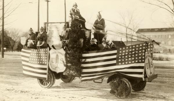 Costumed people pose on a decorated Forest Service parade vehicle.