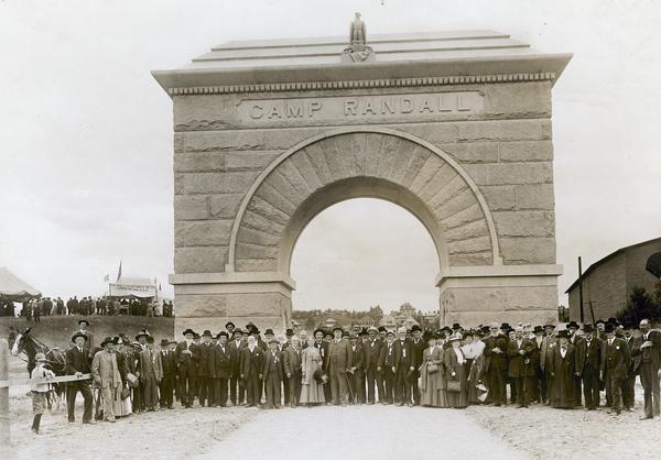 A group of people posing in front of the Camp Randall Memorial Arch during its dedication.