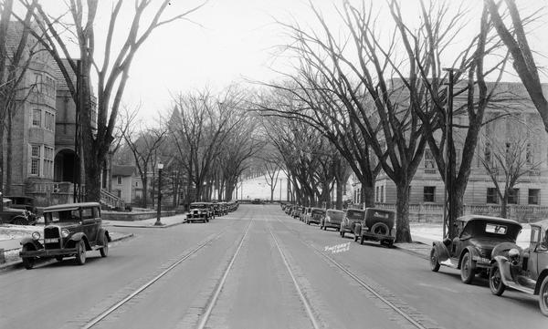 View of State Street with the Wisconsin Historical Society, the University Club, and Bascom Hill in the background. The street is lined with automobiles.