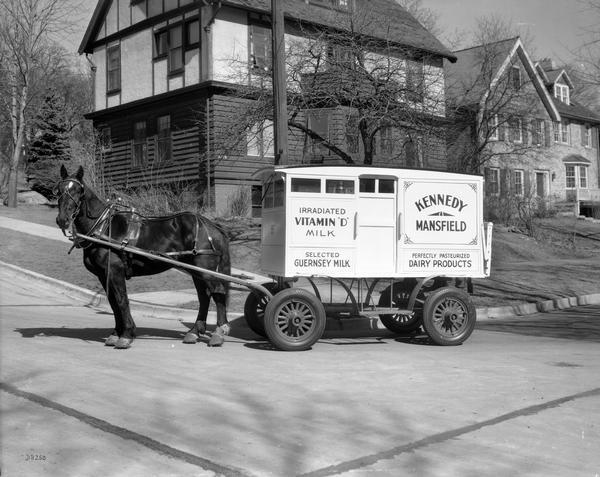 Horse-drawn Kennedy Mansfield milk wagon at 2126 Vilas Avenue on the corner of Vilas and Edgewood. Signage on side of wagon advertises "irradiated Vitamin D milk".