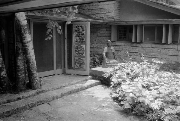 Looking south at the open front door at Taliesin with birch trees on left and Buddha on right of center. Taliesin is located in the vicinity of Spring Green.