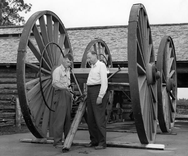 Two men examine a hook attached to a huge wagon, part of a Farm Museum Exhibit at the Wisconsin State Fair.