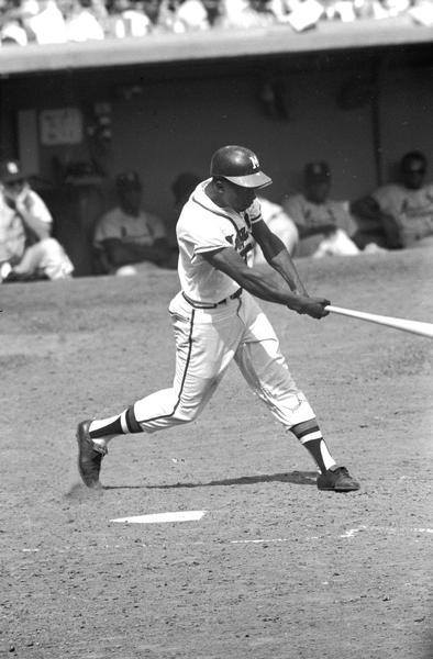 Milwaukee Braves outfielder Henry Aaron swings his bat during a baseball game.