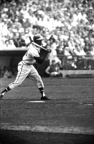 Henry Aaron, as a Milwaukee Brave,  takes a swing at a pitch.