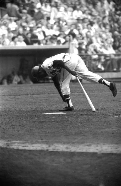 Henry Aaron leaning  down to adjust his sock while at bat as a Milwaukee Brave.